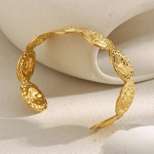 Détail d'un bracelet en acier inoxydable doré 18K avec motif de pièce en relief sur pierre