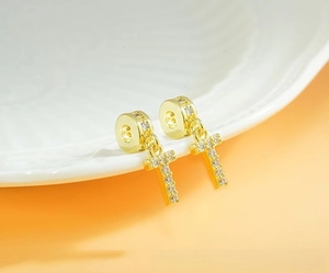Detailed view of gold-plated T-shaped pendant earrings with micro-paved white zircons