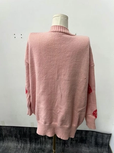 Detailed back view of a pink knitted cardigan showing red strawberry sleeve patterns