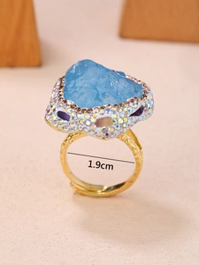 Vue détaillée d'une bague dorée ajustable avec pierre bleue brute et strass colorés