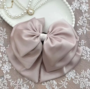 Elegant dusty pink satin multilayer bow hair clip placed on a vintage lace and pearl setting