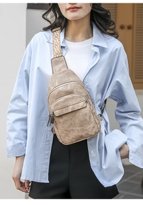 Close-up of beige canvas chest bag with patterned woven strap and zip pockets