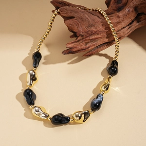Detail of bohemian acrylic chunky necklace with gold and black marble beads on driftwood