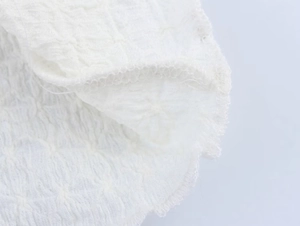 Detailed macro view of white textured crinkle fabric with rolled hem stitching on top