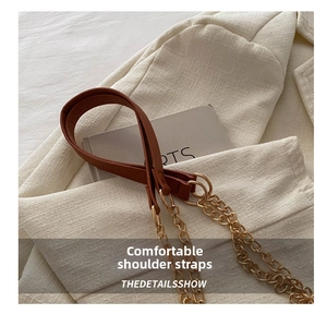 Detail of the brown leather and gold chain shoulder strap on a crossbody handbag