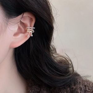Detail of gold bow pearl ear cuff with zircon accents worn on model's ear