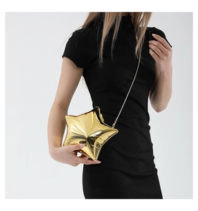 Detail showing high-shine gold star acrylic crossbody bag with slim metal chain on a model