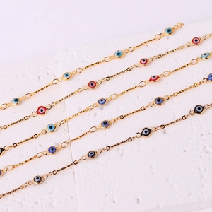 Five gold-plated evil eye link bracelets with colorful beads on a white surface