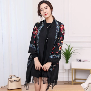 Detail of vibrant floral embroidery on a black cashmere-feel pashmina shawl with tassels