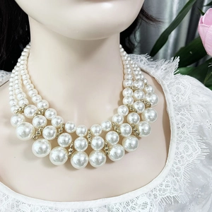 Detailed view of layered white pearl necklace with gold beads worn on a model