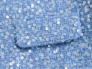 Macro shot of blue tweed fabric featuring detailed sequin embellishments and rich texture