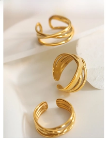 Detailed view of three layered gold crossover open rings on a white textured background