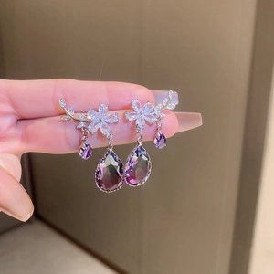 Detail of silver branch flower earrings with purple teardrop crystals held in hand