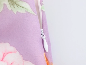 Detail of invisible zipper closure on purple floral woven fabric dress with flower print