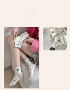 Detail view of white socks featuring black polka dots and delicate embroidered bow accents