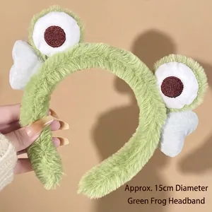 Close-up of a green plush frog headband with white wings and big eyes for skincare