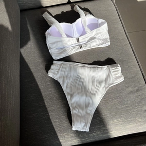Detailed view of white textured bikini top featuring vertical ribbing and metal clasp