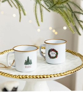 Detail of white enamel mugs with gold rim featuring Christmas tree and Joy motifs