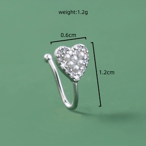 Detail showing silver heart nose ring with inlaid pearls and rhinestones on green background