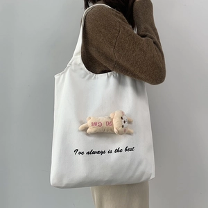 Detail of white canvas tote bag with 3D plush cat doll and black letter print
