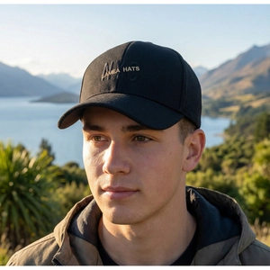 Close-up of golden letter embroidery and textured fabric on a black baseball cap