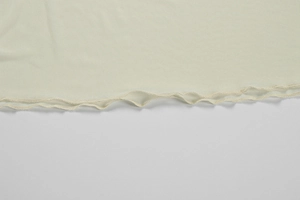 Detailed close-up of the delicate lettuce edge hem on off-white summer dress fabric