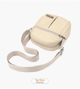 Top view of beige nylon crossbody bag with horizontal and vertical zipper pockets