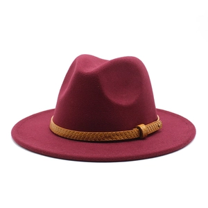 Close-up of burgundy wool fedora hat featuring a brown braided leather band and studs