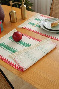 Detail of Christmas table runner with woven holiday tree patterns and cotton tassels