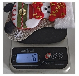 Detail of Christmas snowman plush stocking showing 16g weight on a scale