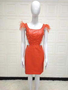 Détail de robe en similicuir orange avec épaules en plumes et glands en strass