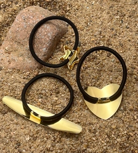 Detailed view of three elastic hair ties with gold star, heart, and bar metal accents