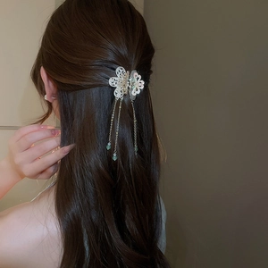 Detailed view of hollow flower hair pin with pearl inlay and elegant metal tassels