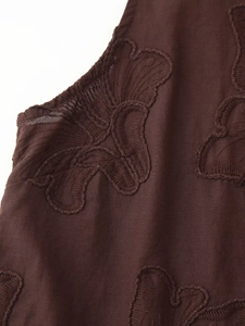 Gros plan détaillé d'une broderie florale brune sur un tissu léger et respirant