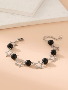 Detail of star-shaped silver links and black beads on a sun moon charm bracelet