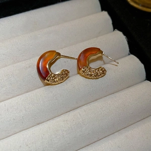 Macro detail of C-shaped leopard style earrings with brown resin and textured gold metal