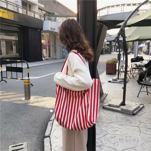 Street style view of large red and white vertical striped canvas tote bag on shoulder