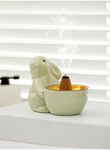 Detailed view of a green ceramic rabbit incense burner with smoke rising from backflow cone