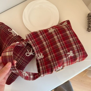Macro shot of red plaid wool fabric with white bow embroidery and brand side label