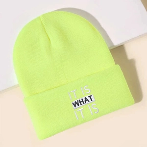 Detail of neon yellow knit beanie featuring IT IS WHAT IT IS embroidery on folded cuff
