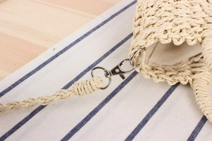 Close-up of woven straw bag showing silver metal clasp and durable fabric lining
