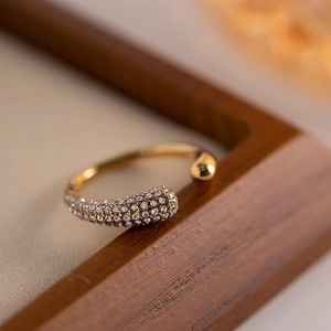 Macro view of gold open ring featuring pavé-set clear stones and a polished bead detail