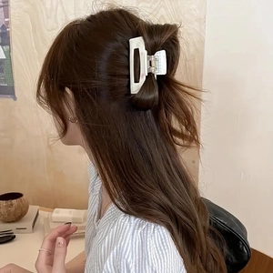 Detail of a white marble texture hair claw clip securing a messy bun in a cozy setting