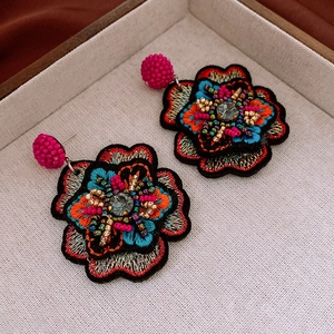 Macro shot of colorful floral embroidery earrings with beads and crystal center details