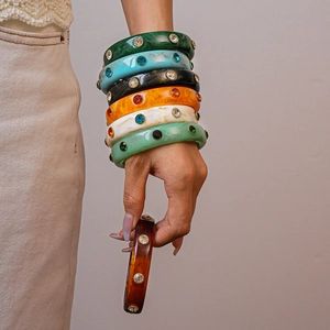 Macro shot of colorful acrylic resin bangles with inlaid rhinestones on a wrist