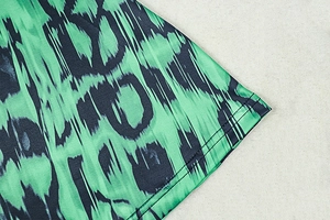 Macro detail of green leopard print fabric with professional double-stitched hem finish