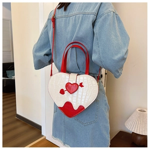Detail of heart-shaped crossbody bag with crocodile texture worn by a model