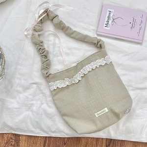 Detail of pink and green plaid canvas bag with white lace trim and satin bow accents