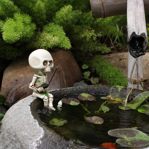 Skull figurine fishing on a stone edge with green moss for garden landscape decoration