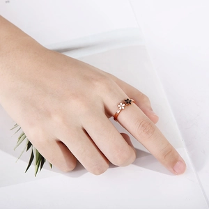 Gros plan d'une bague fleur en or rose avec émail noir et blanc sur une main
